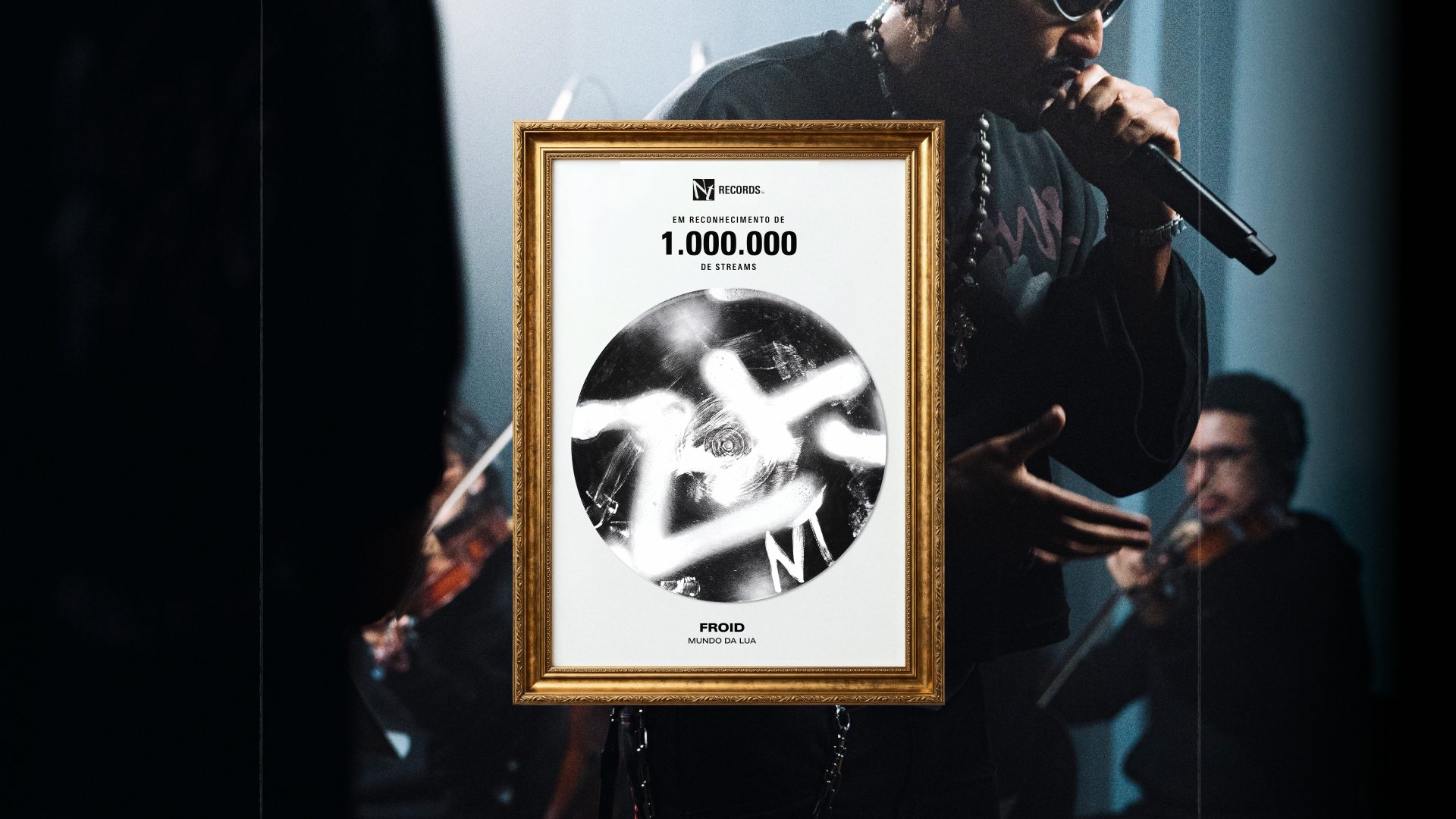 Placa emoldurada da NT Records em reconhecimento a um milhão de streams do artista Froid, sobre foto de show