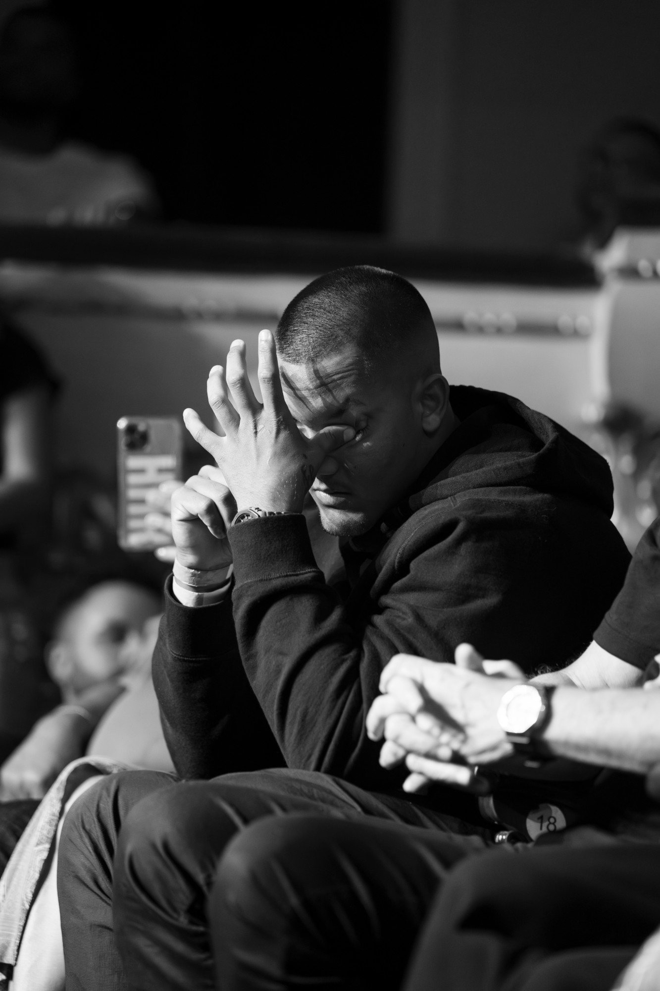 Homem emocionado na plateia, com a mão no rosto, em foto preto e branco